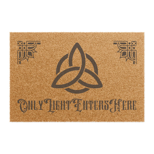 Coir doormat featuring large triple moon and triquetra symbol in center, surrounded by celestial designs including stars and moon phases, all in dark brown on natural tan background.